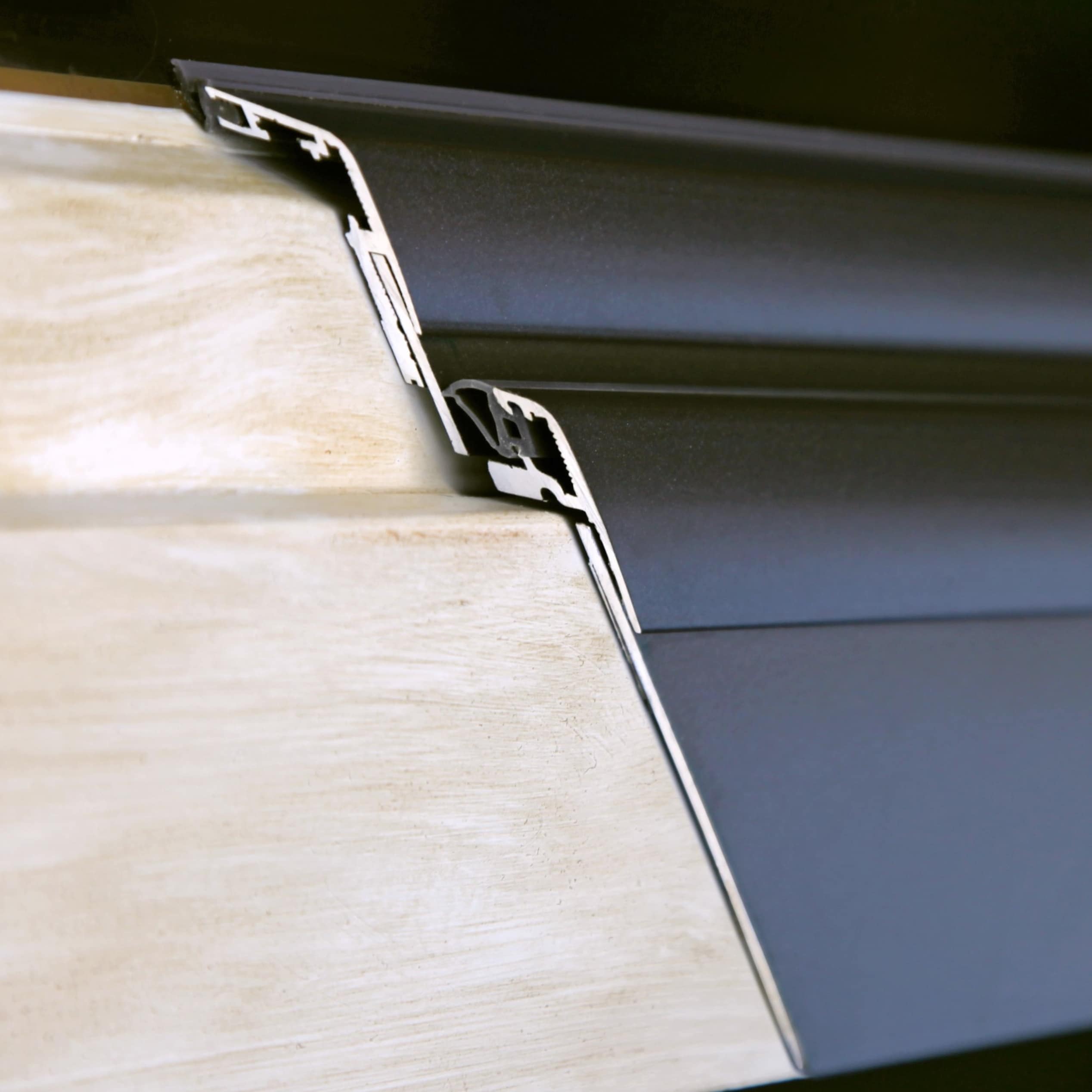 Schnitt durch die Aluminium-Verkleidung auf einem Holzfensterrahmen: links das Holz, rechts die Alu-Schale